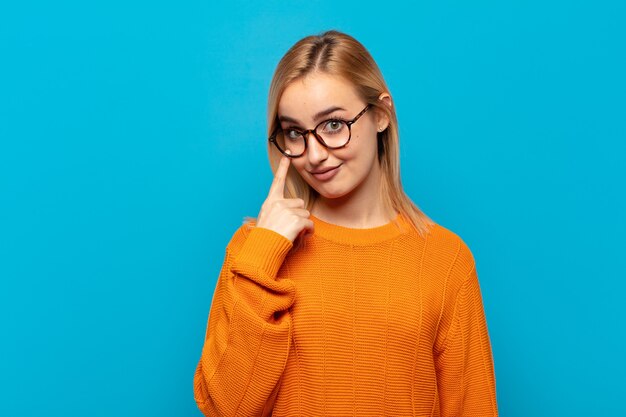 Giovane donna bionda che ti tiene d'occhio, non fidandosi, guardando e rimanendo vigile e vigile