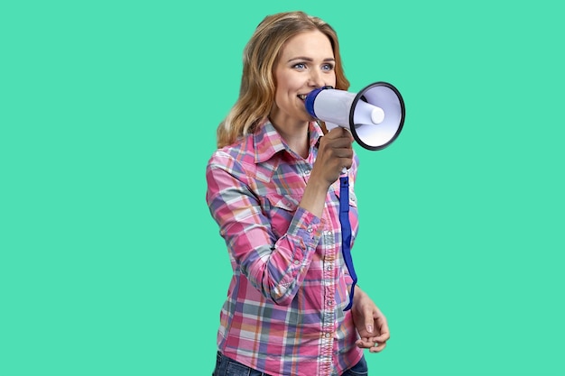 Giovane donna bionda che tiene un megafono e parla isolata su sfondo verde