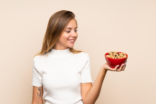 Giovane donna bionda che tiene una ciotola di cereali