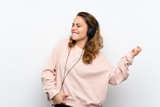 Giovane donna bionda che usando il cellulare con le cuffie e ballare