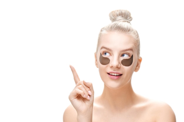 giovane donna bionda con bende oculari nere punta il dito contro lo spazio della copia isolato su sfondo bianco