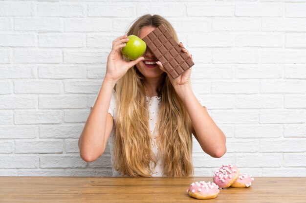 Giovane donna bionda con chocolat e una mela