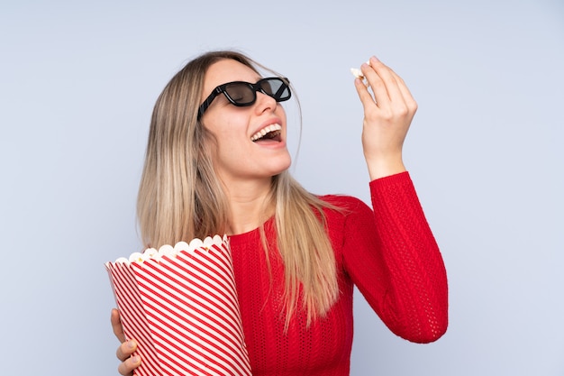 Giovane donna bionda con gli occhiali 3d e in possesso di un grande secchio di popcorn