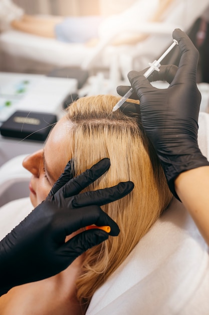 Giovane donna bionda con il problema di perdita di capelli che riceve iniezione