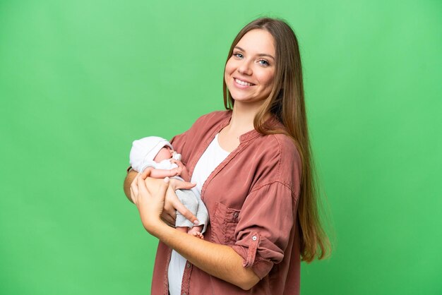 Giovane donna bionda con il suo bambino appena nato su sfondo chroma key isolato che sorride molto