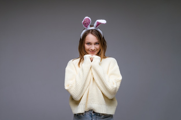 Giovane donna, bionda, con indosso orecchie da coniglio bianche