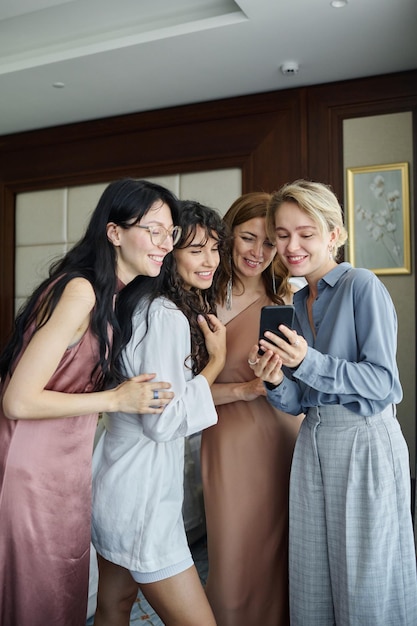 Giovane donna bionda con lo smartphone che mostra nuove foto ai suoi amici