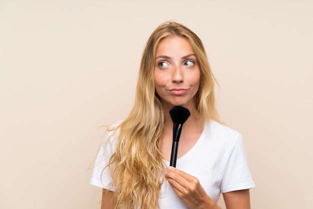 Giovane donna bionda con pennello trucco