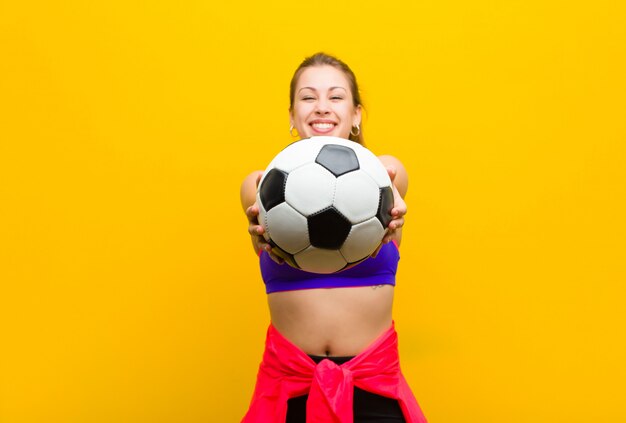 Giovane donna bionda con un pallone da calcio. concetto di sport