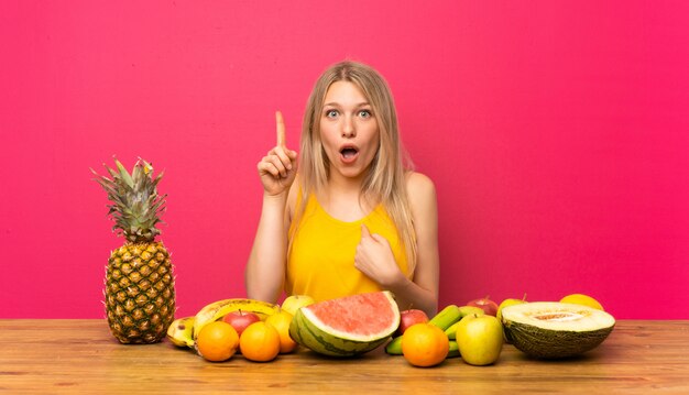 Giovane donna bionda con un sacco di frutti con sorpresa espressione facciale