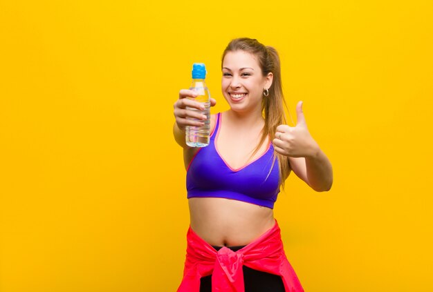 Giovane donna bionda con una bottiglia d'acqua. concetto di sport