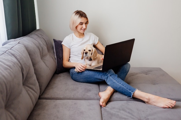 giovane donna bionda con uno spaniel seduto a un laptop blogger che lavora su internet home office