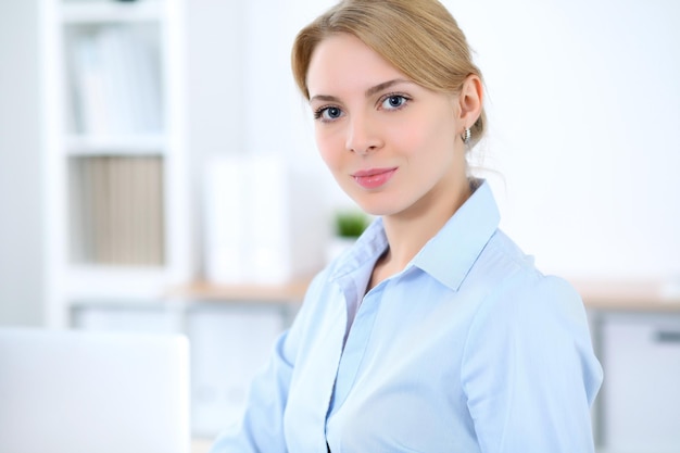 Giovane donna bionda d'affari con il computer portatile in ufficio. Concetto di affari.