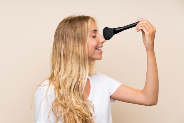 Giovane donna bionda felice con la spazzola di trucco