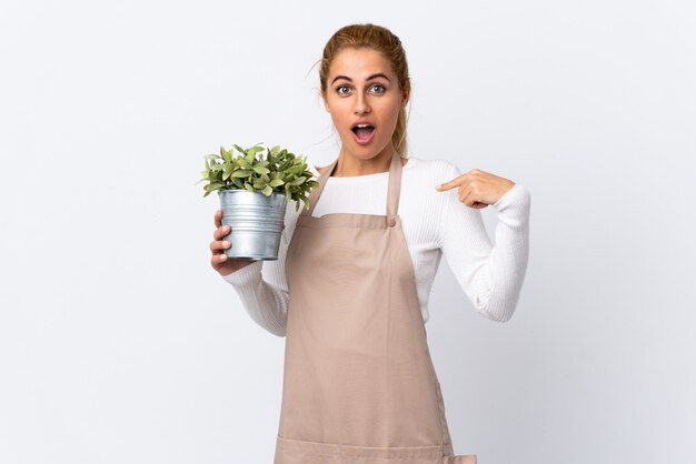 Giovane donna bionda giardiniere donna che tiene una pianta isolata