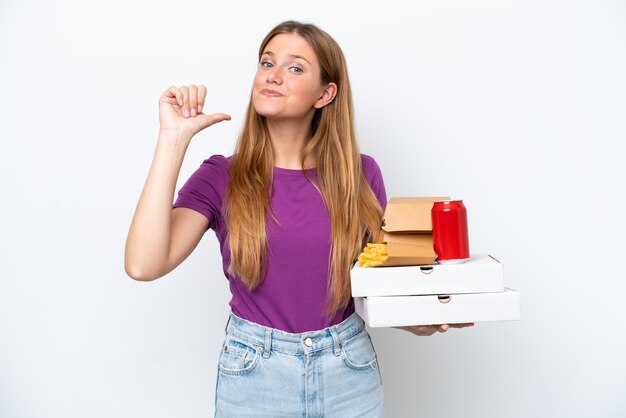 Giovane donna bionda graziosa che tiene fast food isolato su sfondo bianco orgoglioso e soddisfatto di sé