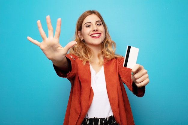 Giovane donna bionda graziosa con la carta di credito