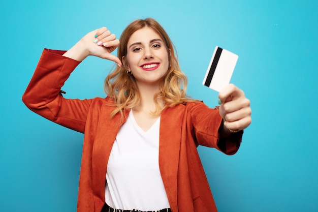 Giovane donna bionda graziosa con la carta di credito