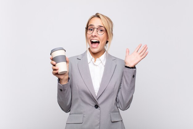 Giovane donna bionda graziosa con un caffè da asporto