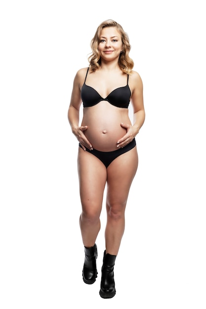 Giovane donna bionda incinta in lingerie nera e scarpe ruvide.