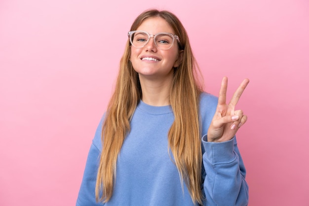 Giovane donna bionda isolata su sfondo rosa Con gli occhiali e facendo segno OK