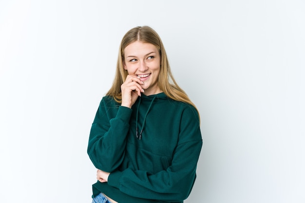 Giovane donna bionda isolata sul muro bianco rilassato pensando a qualcosa guardando uno spazio di copia