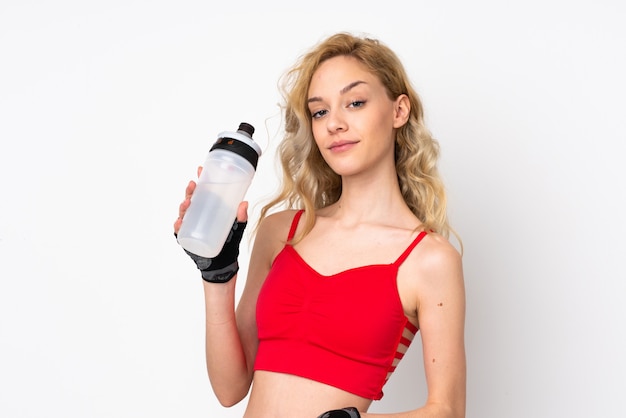 Giovane donna bionda isolata sulla parete bianca con la bottiglia di acqua di sport