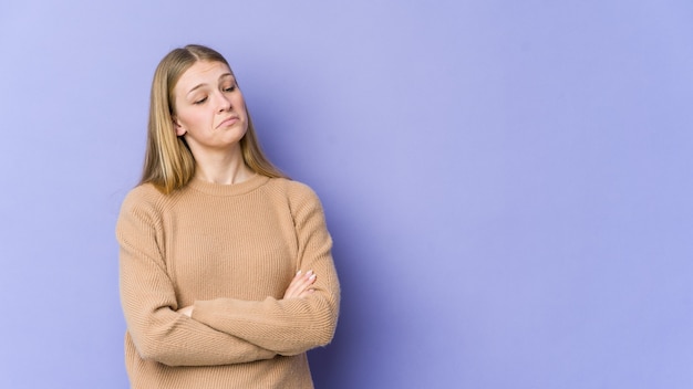 Giovane donna bionda isolata sulla parete viola stanca di un compito ripetitivo.