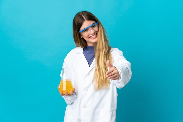 Giovane donna bionda scientifica isolata sulla parete blu che agitano le mani per chiudere un buon affare