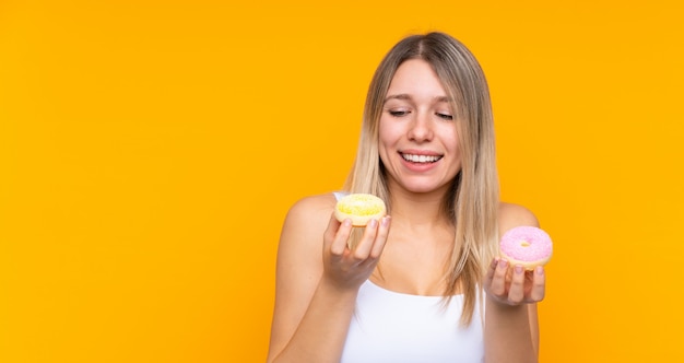 Giovane donna bionda sopra le guarnizioni di gomma piuma isolate della tenuta della parete con l'espressione felice