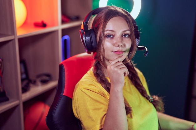 Giovane donna bionda streamer seduta sul tavolo con espressione rilassata nella sala da gioco