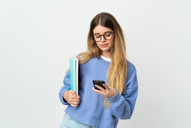 Giovane donna bionda studentessa in posa isolata contro il muro bianco