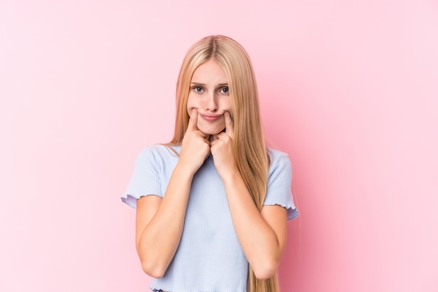 Giovane donna bionda su sfondo rosa dubitando tra due opzioni.