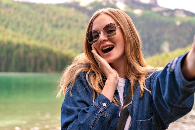 Giovane donna bionda uscita che si diverte e fa selfie al Lago Nero, Montenegro