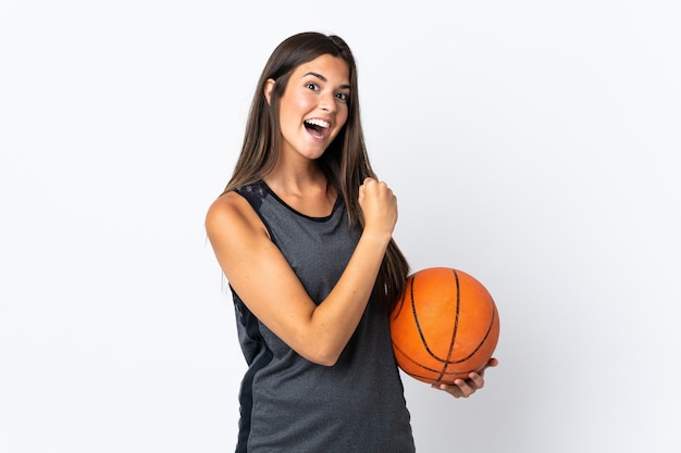 Giovane donna brasiliana che gioca a basket isolato su sfondo bianco che celebra una vittoria