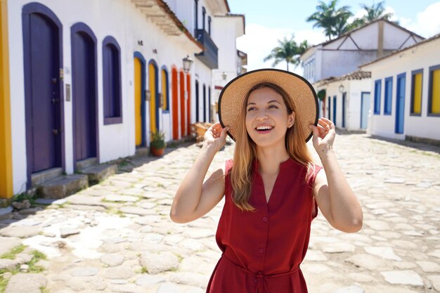 Giovane donna brasiliana che tiene cappello indossando abiti estivi all'aperto