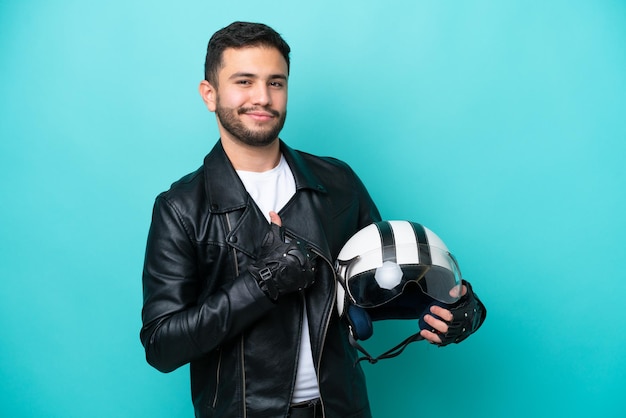 Giovane donna brasiliana con un casco da motociclista isolato su sfondo blu orgogliosa e soddisfatta