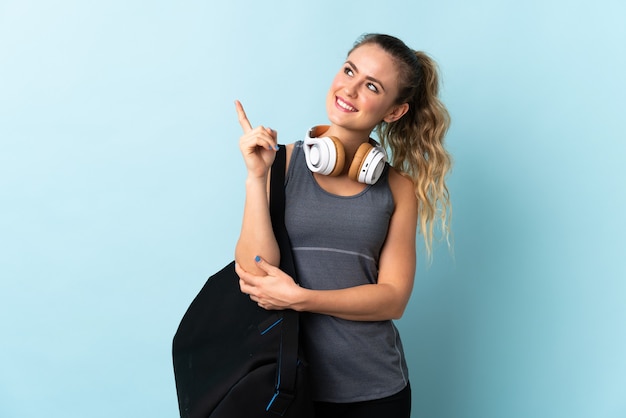 Giovane donna brasiliana di sport con la borsa di sport isolata sull'azzurro che indica su una grande idea