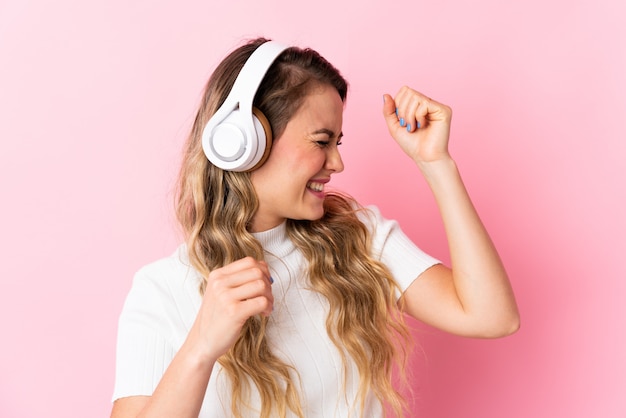 Giovane donna brasiliana isolata su musica e ballare d'ascolto rosa