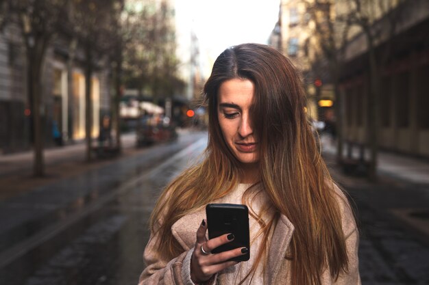 Giovane donna bruna caucasica utilizzando uno smartphone