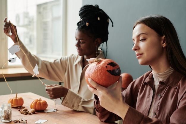 Giovane donna bruna che guarda una zucca inquietante nelle sue mani