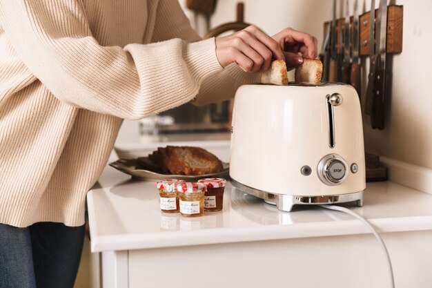 giovane donna bruna fare colazione con toast e marmellate in cucina a casa