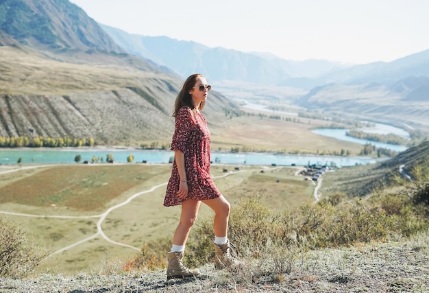 Giovane donna bruna in abito rosso sullo sfondo delle montagne turchesi del fiume Katun Altai