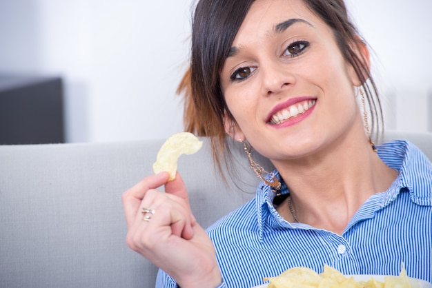 Giovane donna bruna mangiare patatine