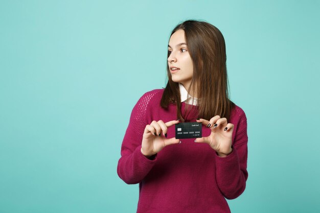 Giovane donna bruna ragazza in abiti casual in posa isolata su sfondo blu turchese ritratto in studio. Persone sincere emozioni concetto di stile di vita. Mock up spazio di copia. Tenere in mano la carta di credito.