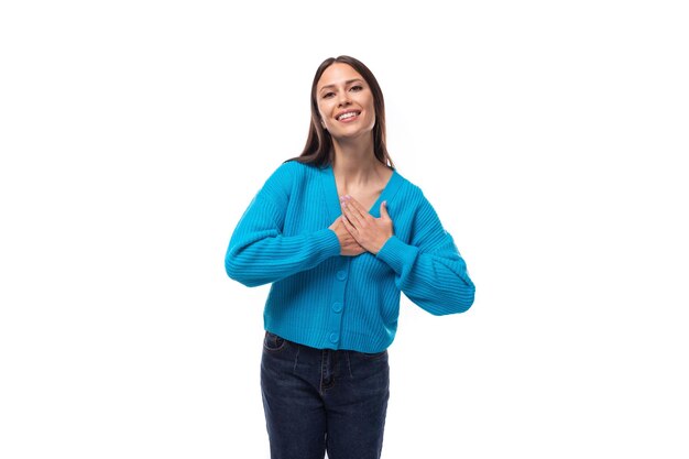 Giovane donna bruna sorridente allegra con trucco leggero è vestito in un maglione blu buttondown su un