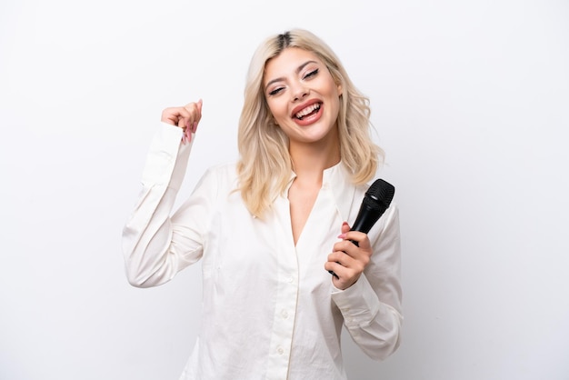 Giovane donna cantante che raccoglie un microfono isolato su sfondo bianco che celebra una vittoria