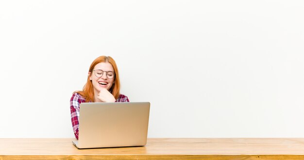 Giovane donna capa rossa davanti a un tavolo di legno