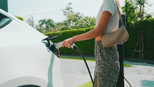 Giovane donna carica la batteria dell'auto EV all'aperto