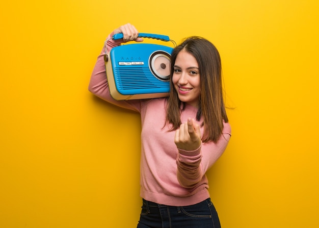 Giovane donna carina che tiene una radio d'epoca che invita a venire